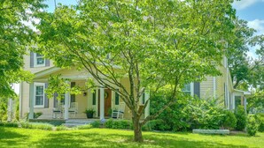 A two-story house with a front porch, a lawn, and a tree. - Bourbon Country Escape! Spacious Home w/ Fire Pit (Taylorsville)