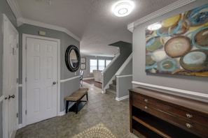 A hallway with a white door, a bench, a staircase, and a painting on the wall. - 3 Mi to Butler U: Family-Friendly Indy Home (Indianapolis)