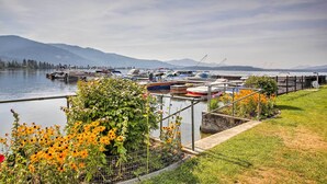 Een jachthaven met stilgelegde boten, een gazon met bloemen en bergen op de achtergrond.