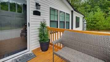 A wooden deck with a wicker chair and a potted plant.