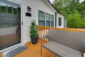 Une terrasse en bois avec une chaise en osier et un pot de fleurs.