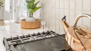 A kitchen with a stove, a plant, and a kettle. - Hot Tub BBQ Island Outdoor Living Near San Diego Beaches Glidden Glow by Avantstay (San Diego)