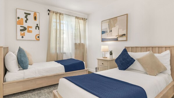 A hotel room with two beds, a nightstand, a lamp, and artwork on the walls. - Hot Tub BBQ Island Outdoor Living Near San Diego Beaches Glidden Glow by Avantstay (San Diego)