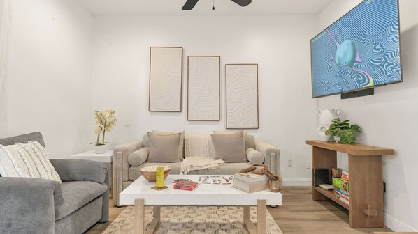 A living room with a grey sofa, a white coffee table, and a bookshelf. - Hot Tub BBQ Island Outdoor Living Near San Diego Beaches Glidden Glow by Avantstay (San Diego)