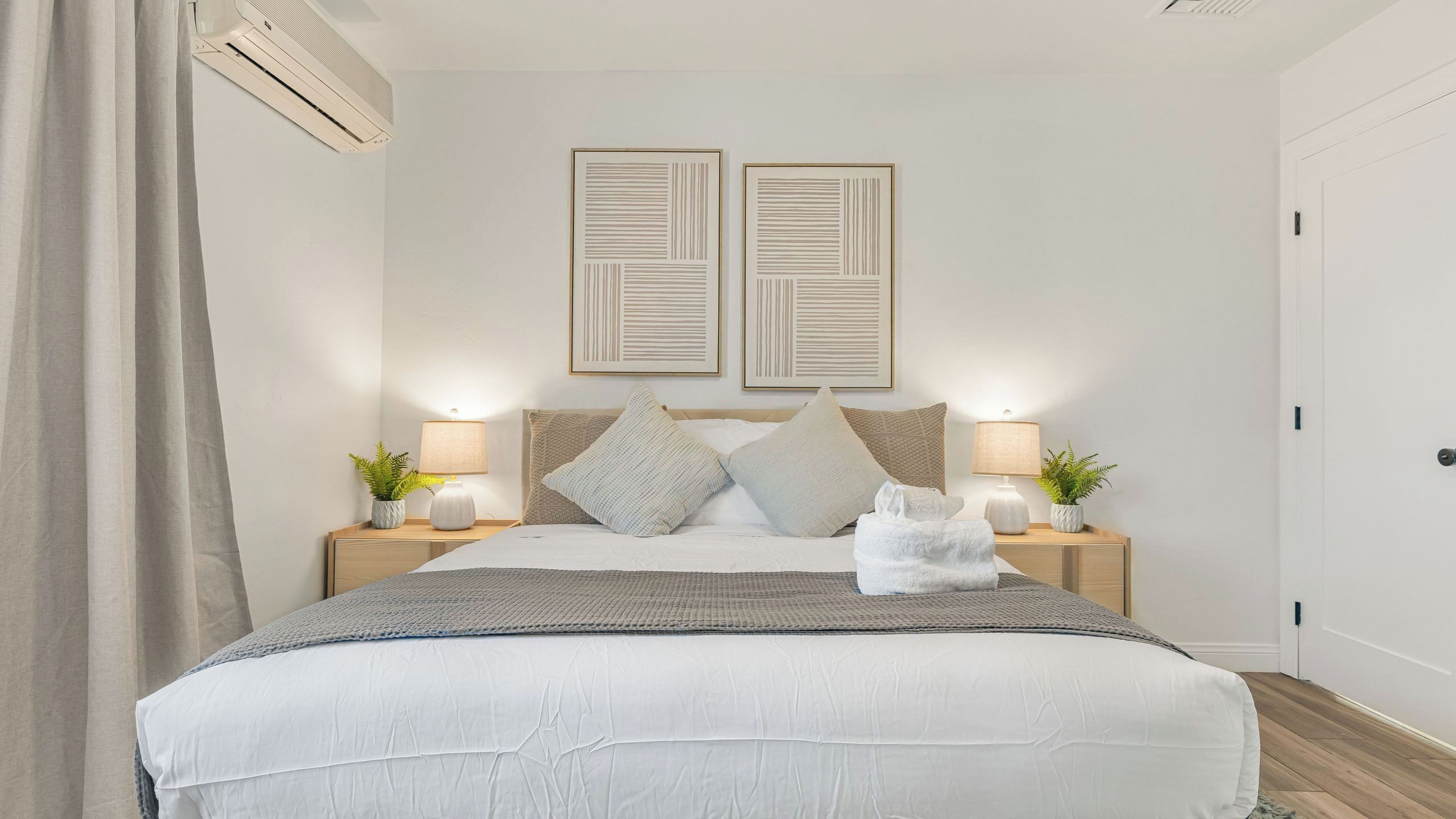 Quarto bem arrumado com uma cama, mesas de cabeceira, abajures e duas obras de arte emolduradas na parede.