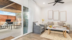 A modern living room with a grey sofa, a coffee table, and a balcony with a barbecue grill. - Hot Tub BBQ Island Outdoor Living Near San Diego Beaches Glidden Glow by Avantstay (San Diego)