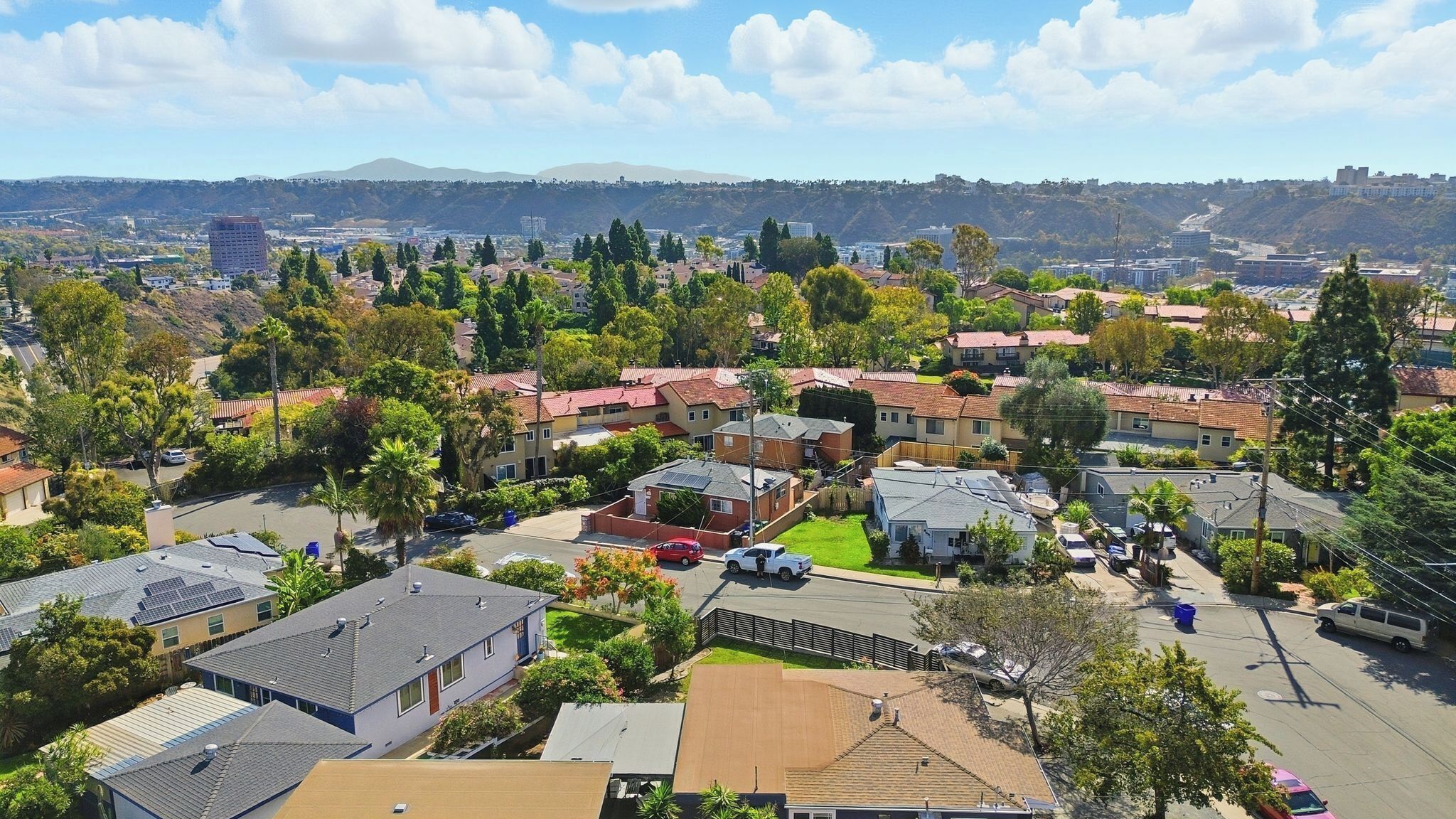A residential area with houses, streets, and a hilly landscape in the background.