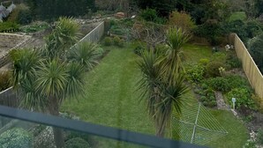 Un jardín con vista al mar, una valla de madera y diversas plantas.