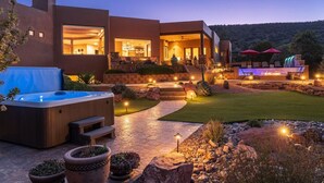 Una casa moderna con jacuzzi, mobiliario exterior y zona con chimenea.