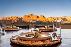 A dining table set with plates, cutlery, and glasses, with a view of a mountainous landscape. - 5.5k Sqft Luxury Home with Large Suites, Views, Hot Tub & Firepit (Sedona)