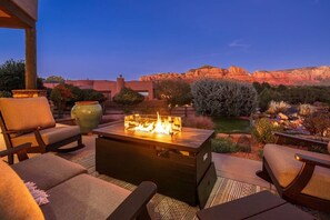 An outdoor seating area with a fire feature, surrounded by a landscaped garden and a view of rock formations. - 5.5k Sqft Luxury Home with Large Suites, Views, Hot Tub & Firepit (Sedona)