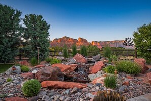 A garden with a small waterfall, rocks, and trees. - 5.5k Sqft Luxury Home with Large Suites, Views, Hot Tub & Firepit (Sedona)