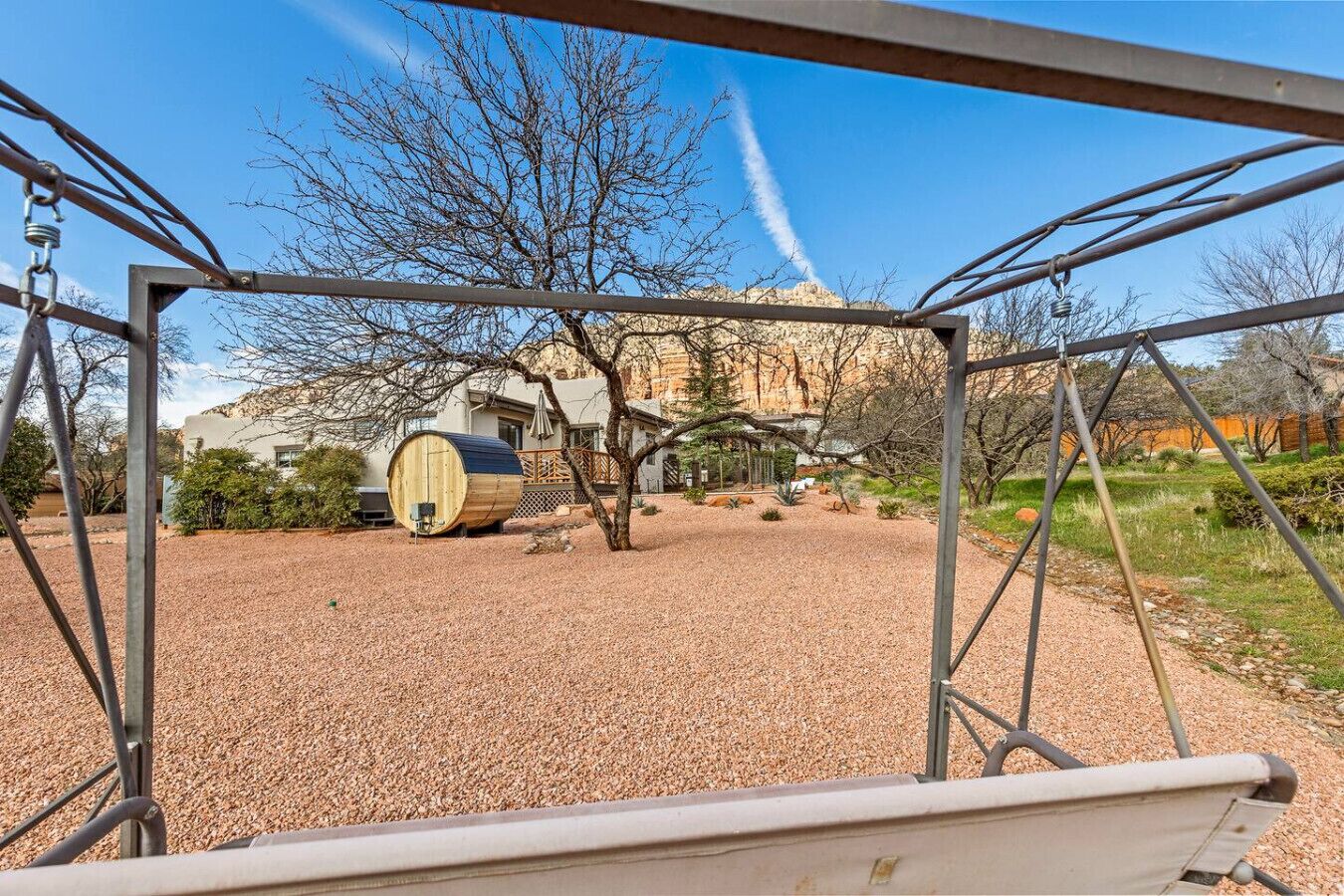 Une vue à travers une structure métallique, avec un tonneau en bois et une maison en arrière-plan.