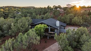 A modern house surrounded by dense trees, with a clear view of the surrounding landscape. - Hillside Haven | Wellness Spa, Pickleball, Games (Sedona)