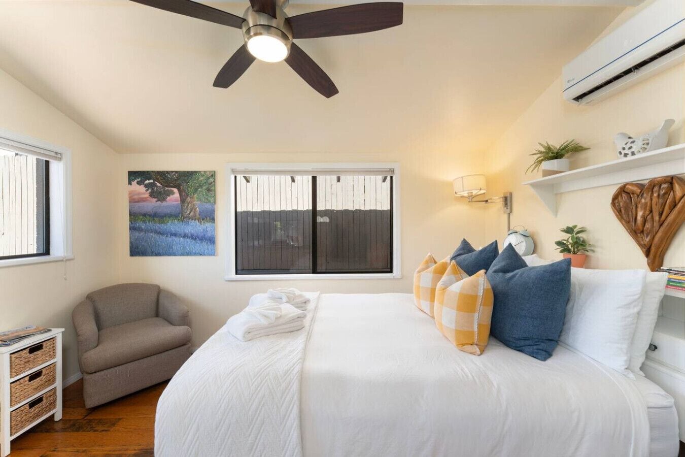 A bedroom with a bed, a chair, a window, and a ceiling fan.