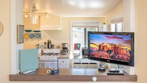 Eine moderne Küche mit Gasherd, Kaffeemaschine und einem Flachbildfernseher, der eine schöne Landschaft zeigt.