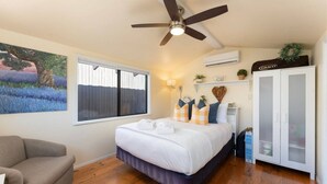 Ein Schlafzimmer mit Bett, Deckenventilator, Fenster, Klimaanlage, Kleiderschrank und einem Bild an der Wand.