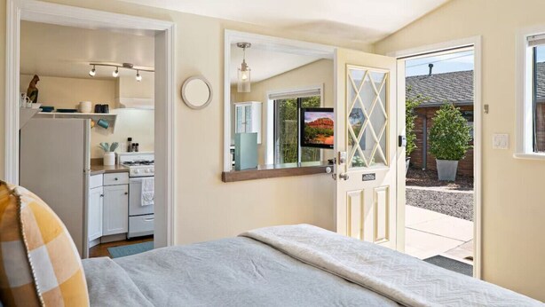 Ein kleines Hotelzimmer mit Bett, Küchenzeile, Bad und Blick ins Freie.