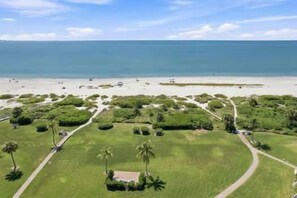 Ein Luftbild einer Küstenimmobilie mit Strand, grünen Rasenflächen und blauem Himmel.