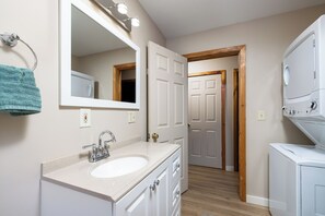A bathroom with a sink, mirror, and a washing machine.