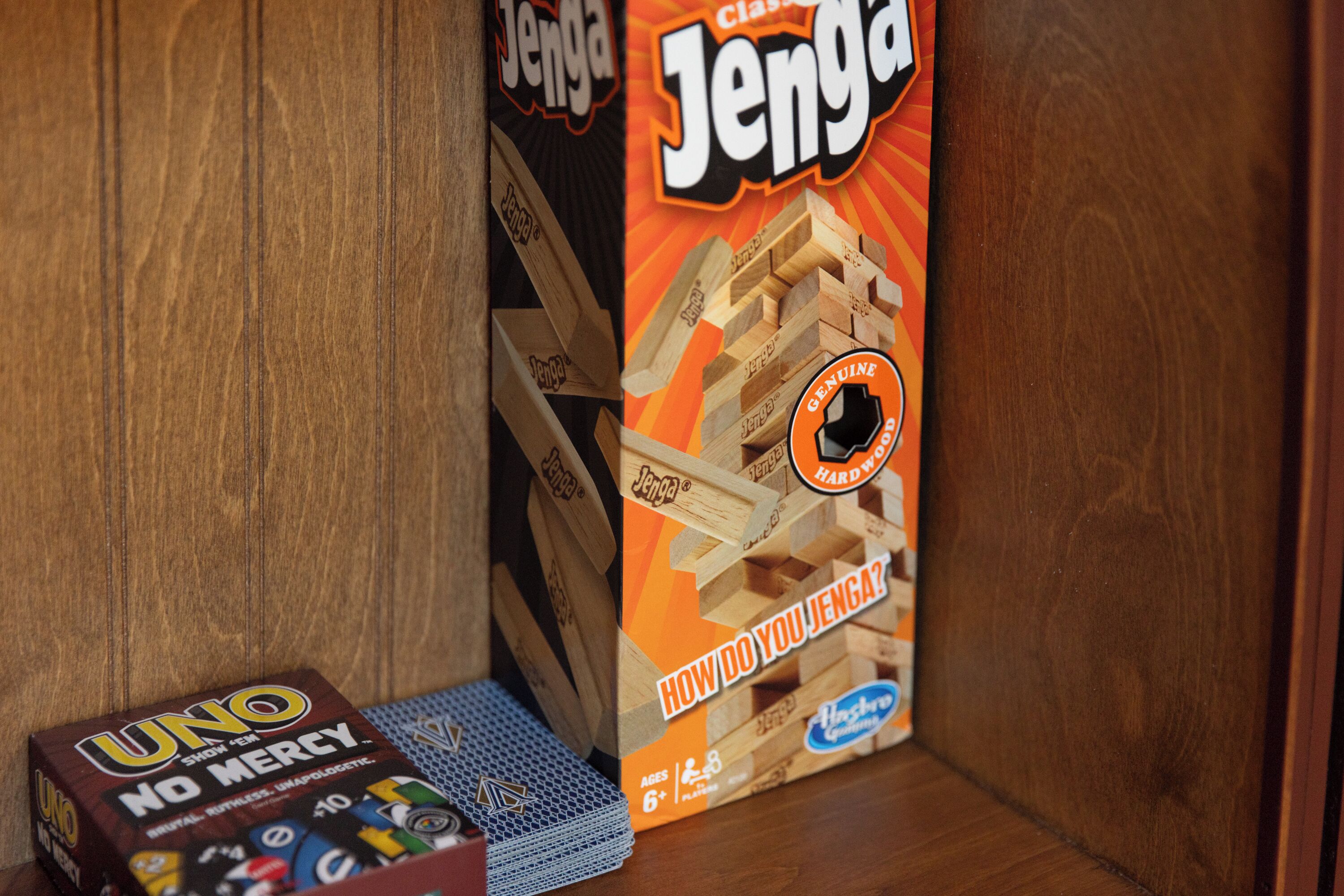 A wooden shelf with a Jenga box and a UNO box.