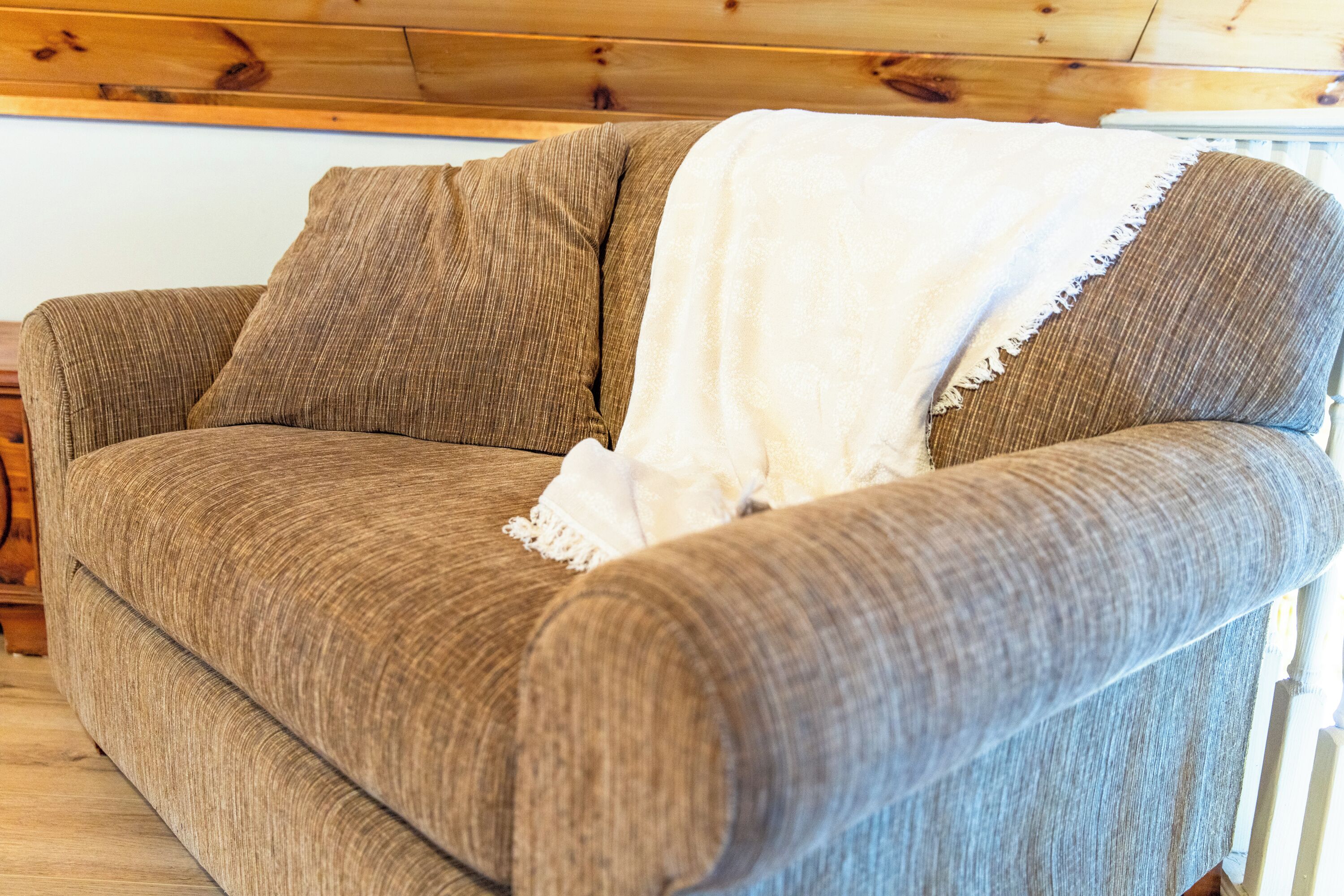 Ein braunes Sofa mit einer weißen Tagesdecke.