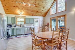 A kitchen with wooden cabinets, a dining table with chairs, and a large window.