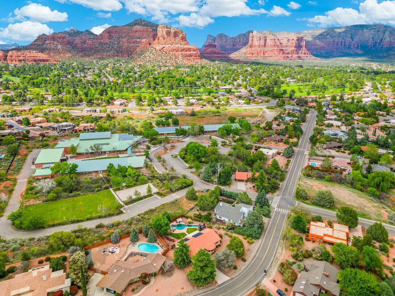 An aerial view of a residential area with houses, roads, and green spaces.