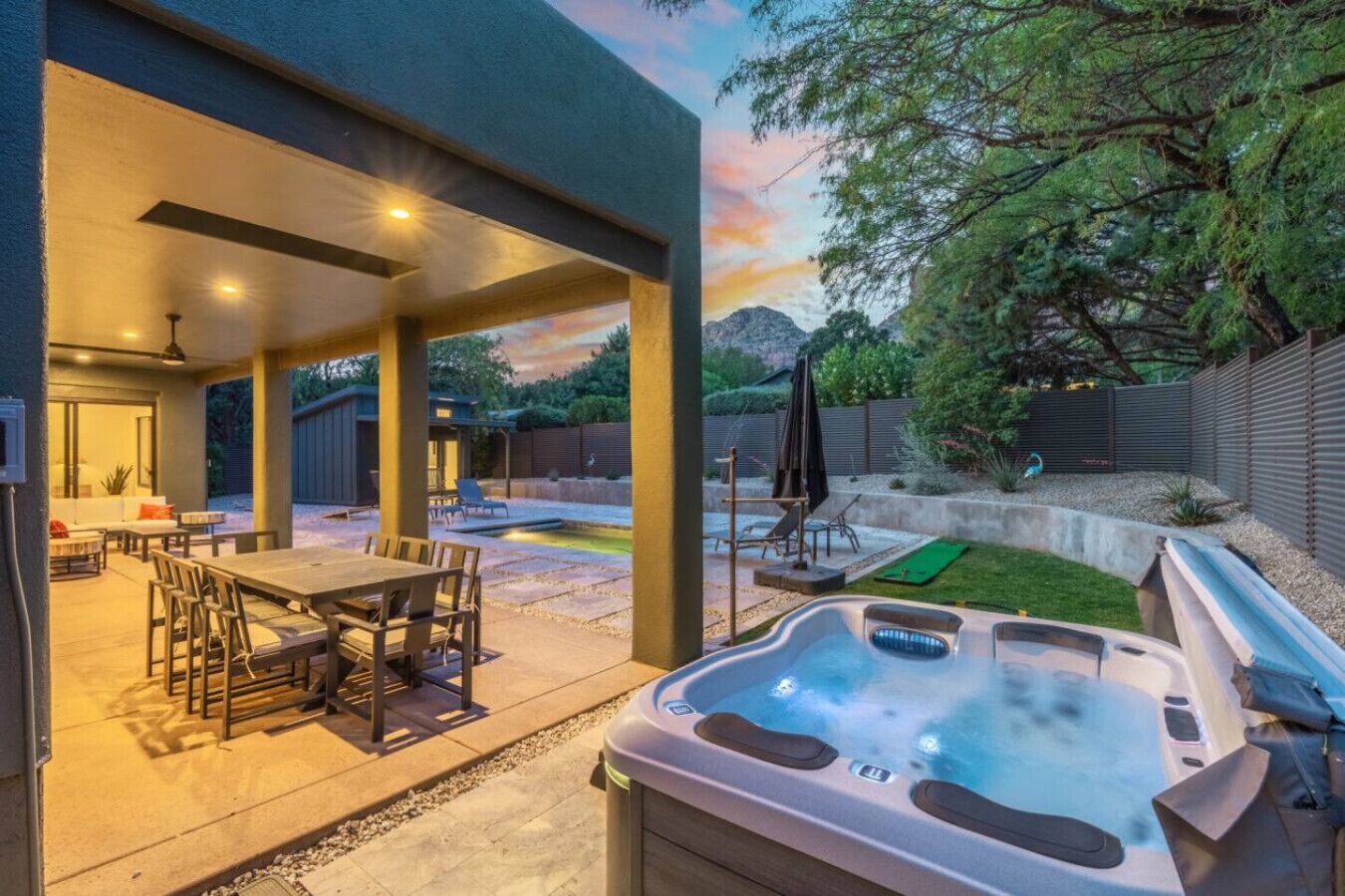 Un espace extérieur aménagé avec un patio, un jacuzzi, un coin salon couvert et une piscine.