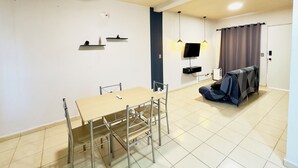 Uma sala de estar moderna com área de jantar, ventilador de teto, TV de tela plana e espaço de estar coberto ao ar livre.