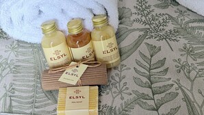 Un juego de artículos de aseo personal ordenado sobre una cama con una colcha de estampado floral.