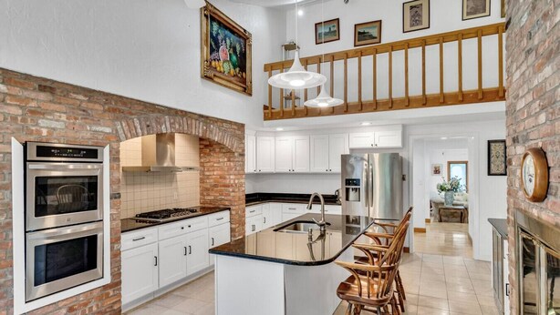 A spacious kitchen with a central island, white cabinets, a brick accent wall, and a hanging light fixture. - Spacious, Quiet, 4BR+office, 1.5 acres yard (Lincoln)