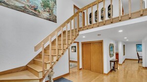 A spacious interior with a wooden staircase, a large painting, and a polished wooden floor. - Spacious, Quiet, 4BR+office, 1.5 acres yard (Lincoln)