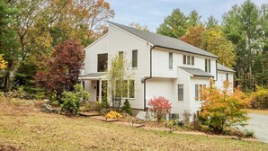 A two-story white house with a gabled roof, surrounded by autumn foliage and a well-maintained lawn. - Spacious, Quiet, 4BR+office, 1.5 acres yard (Lincoln)