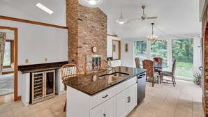 A kitchen with a central island, white cabinetry, a brick accent wall, and a dining area with chairs and a table. - Spacious, Quiet, 4BR+office, 1.5 acres yard (Lincoln)