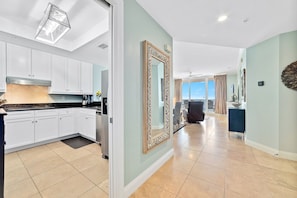A modern kitchen with white cabinets, a black countertop, and a stainless steel refrigerator. - Beach Front Indigo Condo A Week in Paradise Perdido Key Florida (Pensacola)