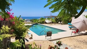 A pool area with a view of the ocean, surrounded by greenery and outdoor seating. - Siren Casita - Incredible Ocean Views, A/C & Heated Saltwater Pool (Todos Santos)