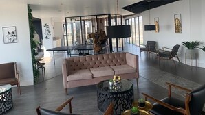 Et rummeligt loungeområde med stor sofa, rundt sofabord og siddepladser.