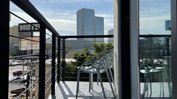 En balkon med udsigt over bybilledet, inklusive en høj bygning og et motel-skilt.