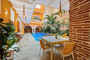 A pool area with a table and chairs, surrounded by plants and a brick wall. - 15BR Mansion in the Walled City / Staff Included (Cartagena de Indias)