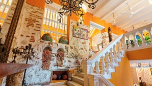 Un edificio histórico con paredes de ladrillo visto, una escalera con barandillas blancas y un candelabro.