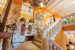 A historic building with exposed brick walls, a staircase with white balustrades, and a chandelier. - 15BR Mansion in the Walled City / Staff Included (Cartagena de Indias)