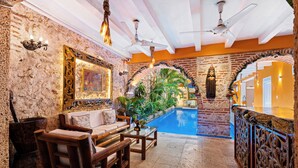 Una habitación con piscina, muebles de madera y arcos decorativos.