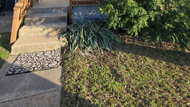 Una casa de dos pisos con un balcón, una puerta principal y un pequeño jardín.