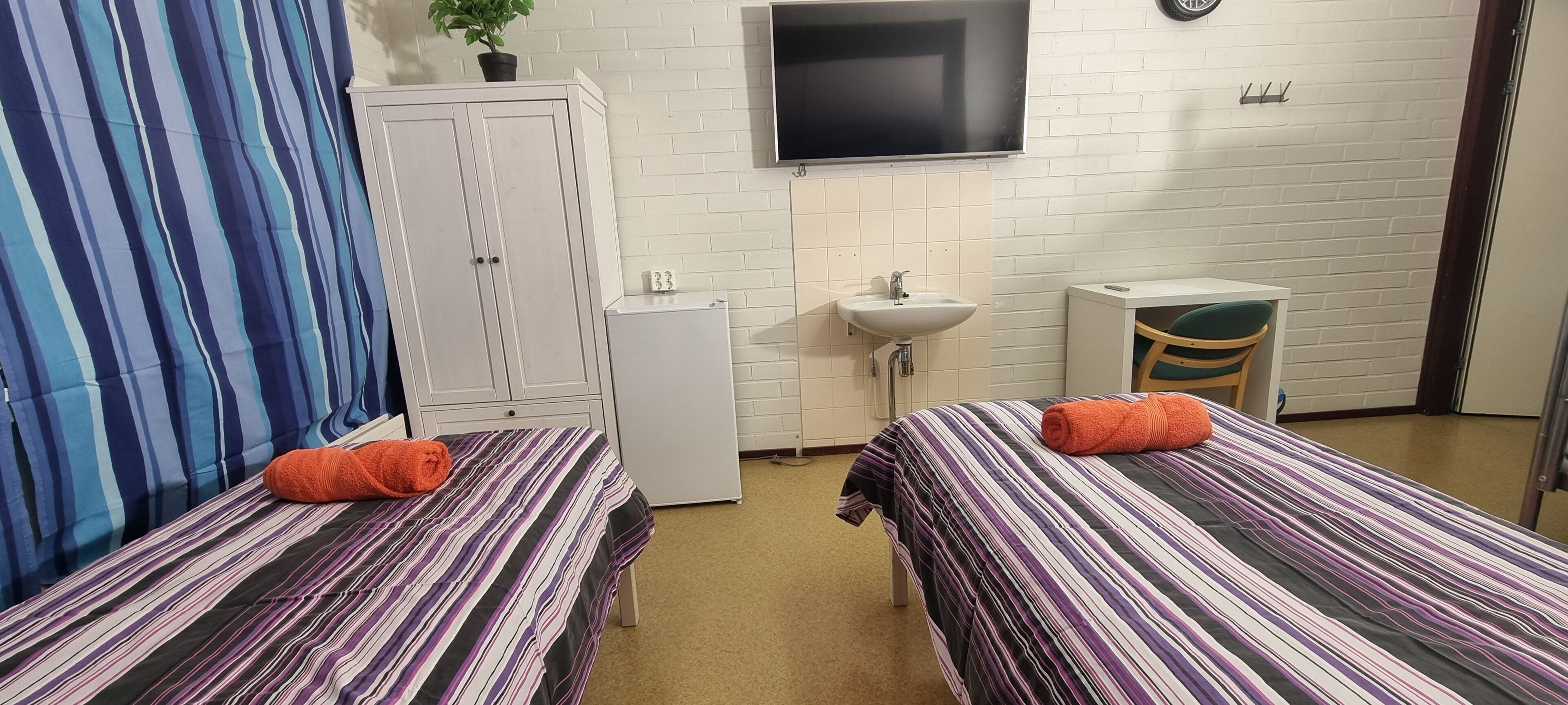 A room with two beds, a TV, a sink, and a small cabinet.