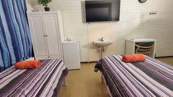 A room with two beds, a TV, a sink, and a small cabinet.