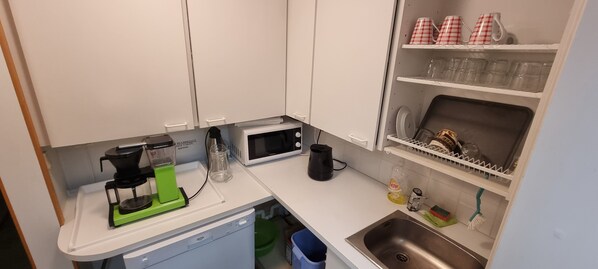Une cuisine compacte équipée d’un four à micro-ondes, d’une machine à café et d’un évier.