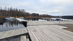A wooden dock extending into a calm lake with a forest in the background.