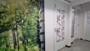 A hallway with doors numbered 2 and 3, a green exit sign, and a map on the wall.