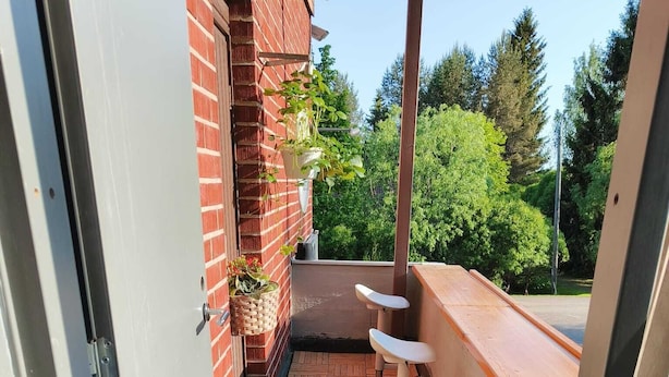 A wooden deck with a herringbone pattern, a brick wall, and a metal railing.